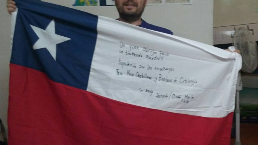 Marc Castellnou sostenint una bandera de Xile dedicada per la seua col·laboració. FOTO: BOMBERS DE LA GENERALITAT