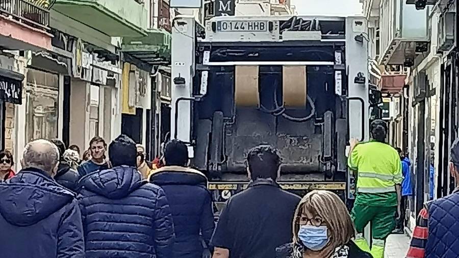 Un camión de basura en la calle peatonal llena de personas.