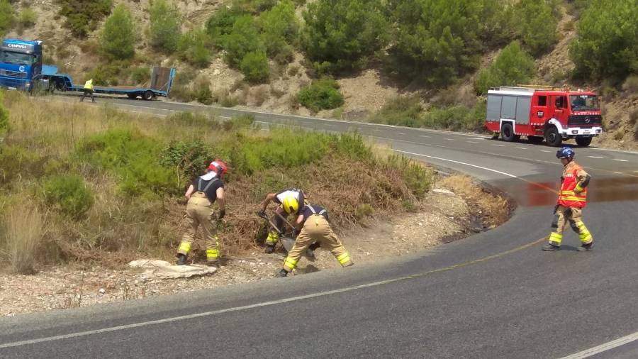 Los bomberos trabajando para limpiar la carretera del aceite vertido. Foto: &Agrave;ngel Juanpere