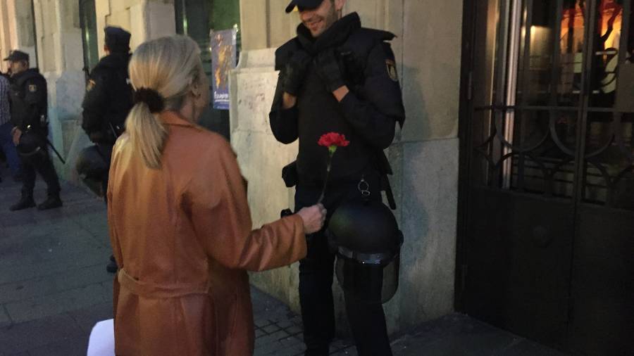 Una mujer entrega un clavel a uno de los agentes de la Polic&iacute;a Nacional. Foto: Carla Pomerol