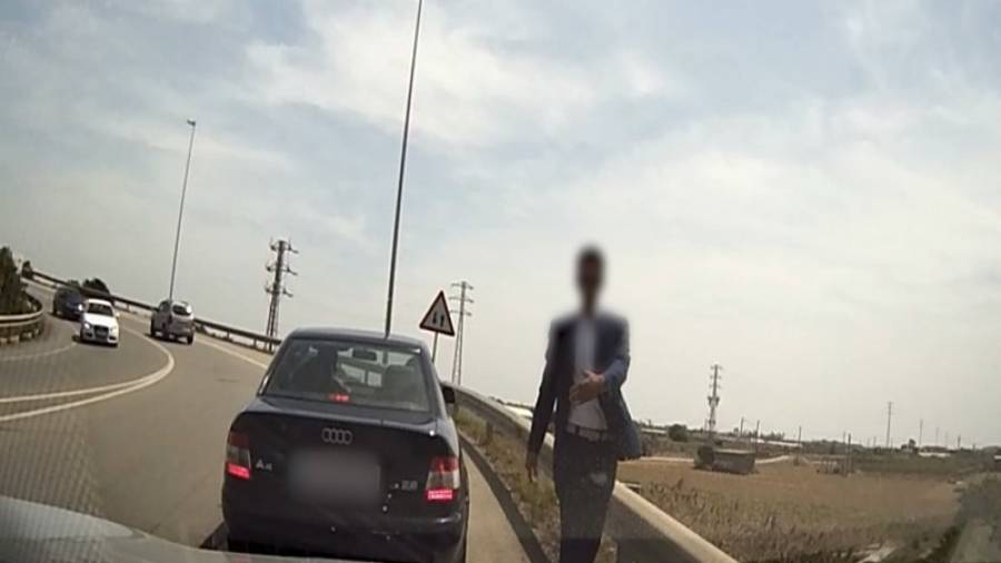 Un dels falsos policies intentant aturar un vehicle. Foto: Mossos d'Esquadra