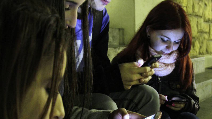 Varios jóvenes consultan sus teléfonos en Tarragona. Foto: Pere Ferré