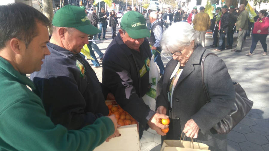 Pagesos donant mandarines a una vianant, ahir al passeig de Gràcia de Barcelona. FOTO: UNIÓ DE PAGESOS