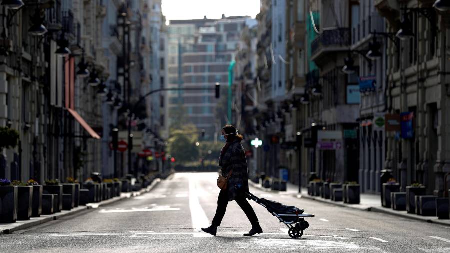 Una mujer, camino de la compra, cruza una completamente desértica calle de la Paz de Valencia. FOTO: EFE