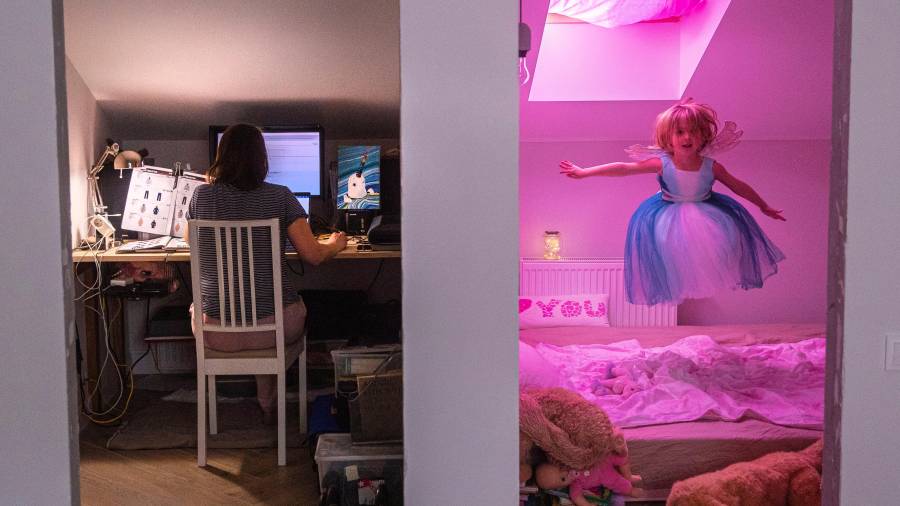 Una mujer trabaja en casa mientras su hija juega en la habitación contigua. Las madres están llevando el mayor peso de la conciliación. FOTO: EFE