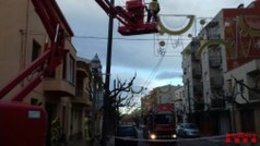 Los bomberos retirando las luces de Navidad de la calle Reus, en La Pobla de Mafumet.
