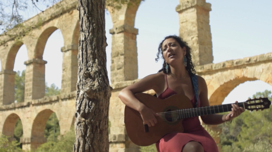 La cantant amb la seva guitarra i de fons l'aqüeducte tarragoni.