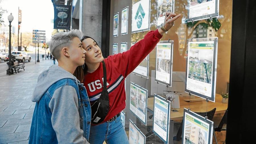 Dos jóvenes miran anuncios de pisos en una inmobiliaria. Foto: Alba Mariné