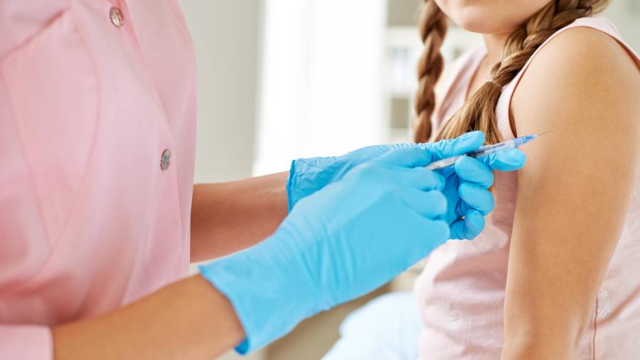 Una enfermera administra una vacuna a una niña.