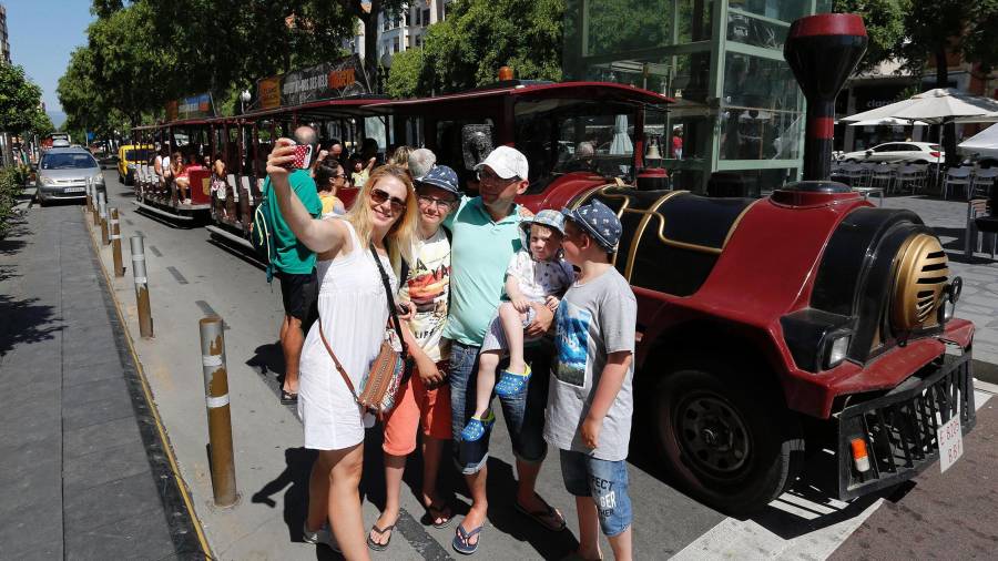 Una familia de turistas se hace un selfie ante el trenet en la Rambla Nova de Tarragona