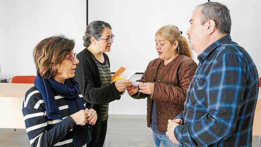 A la derecha, dos usuarios, Ligia Maria Dos Santos y Ramon Domínguez, hablando con dos técnicas de Benestar Social. FOTO: Alba Mariné