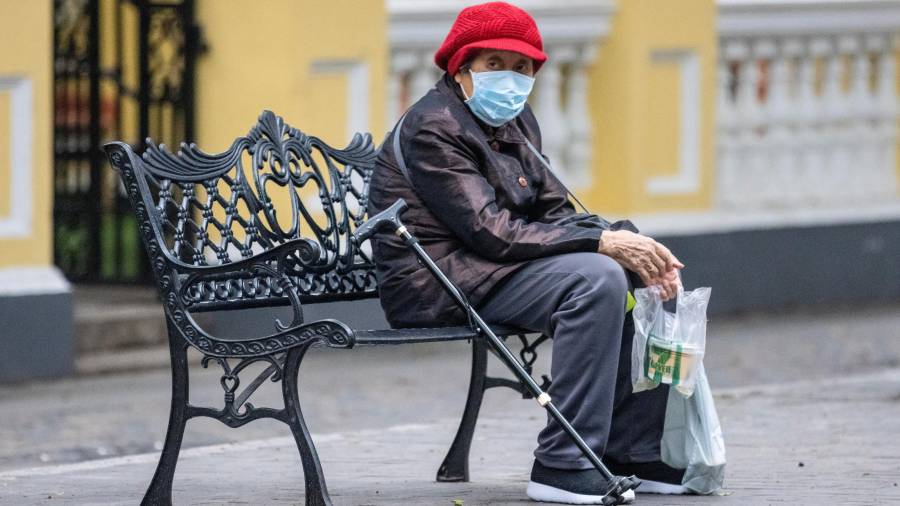 Una mujer sentada en un parque con una m&aacute;scara en la cara en Guangzhou, China. FOTO: CEDIDA