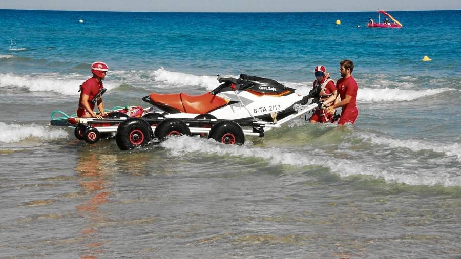 Socorristes de Creu Roja entrant una moto aqüàtica al mar. FOTO: ACN