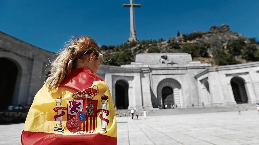 Una visitante del Valle de los Caídos envuelta en una bandera española. FOTO: efe