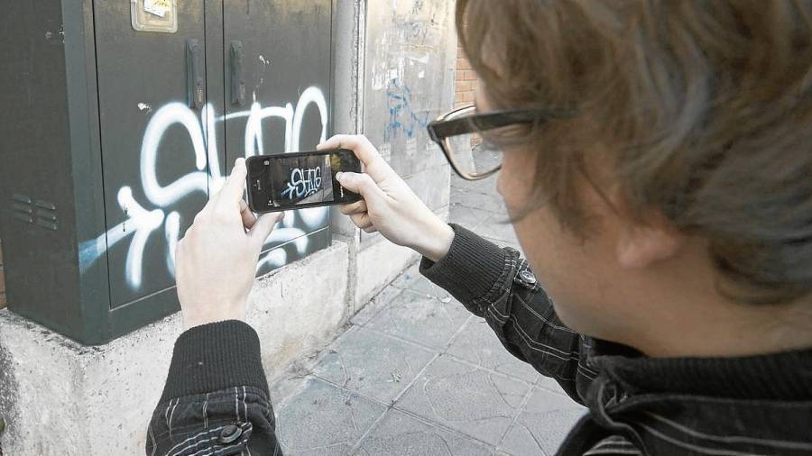 Un ciutadà fent una fotografia d’un grafit per informar el seu Ajuntament. FOTO: Joan Revillas