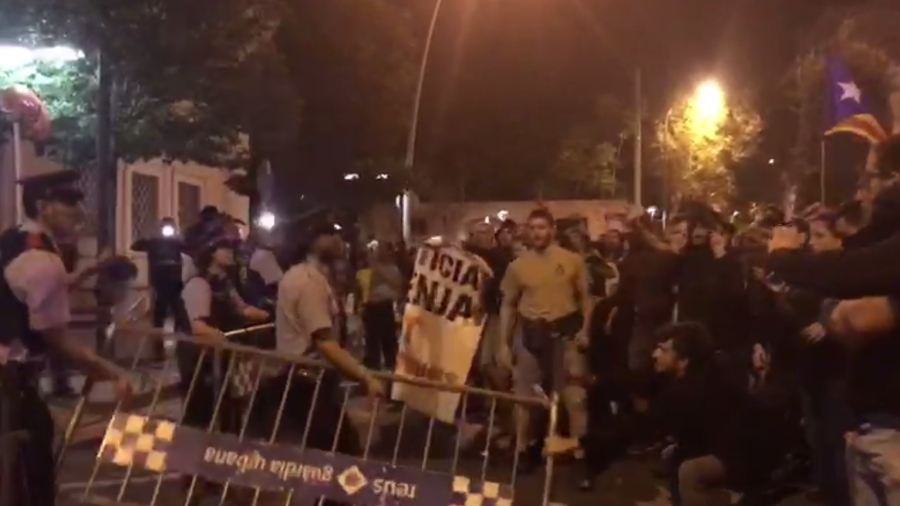 Un mosso y un manifestante tirando de una valla de seguridad.