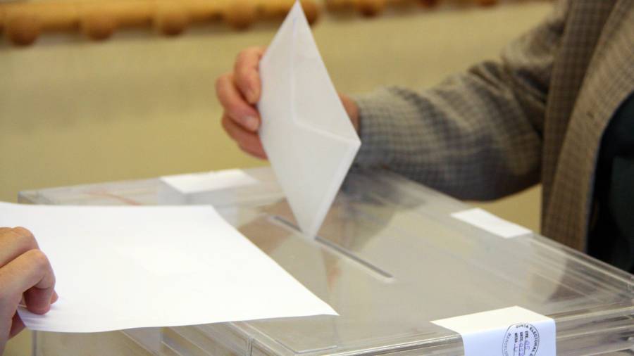 Pla detall de la mà d'un votant amb el sobre a punt de ser introduït a l'urna. Imatge d'arxiu