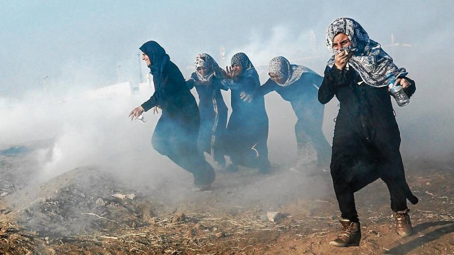 Manifestantes palestinas se cubren la cara a causa de los gases lacrimógenos. Foto: Mohammed Saber / EFE