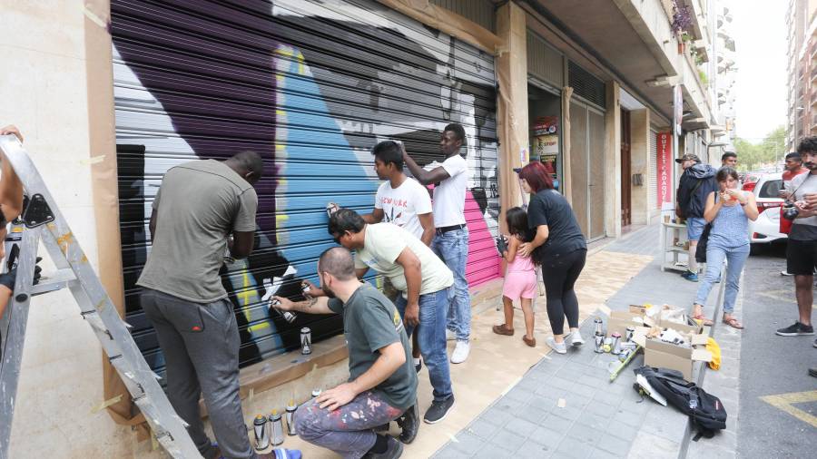 Joves pintant el primer mural de la iniciativa: la de la Cooperativa El Brot, al carrer Pròsper de Bofarull de Reus. FOTO: ALBA MARINÉ