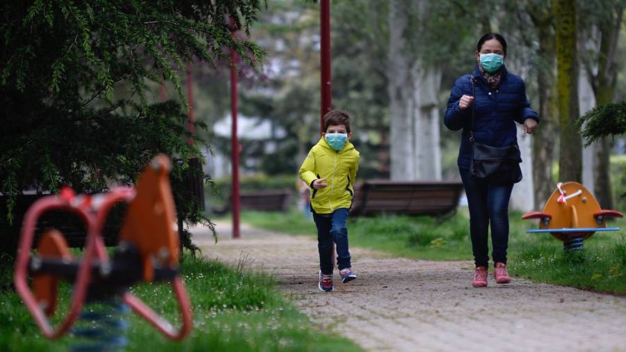 Una mujer y un niño corren por un parque. FOTO: EFE