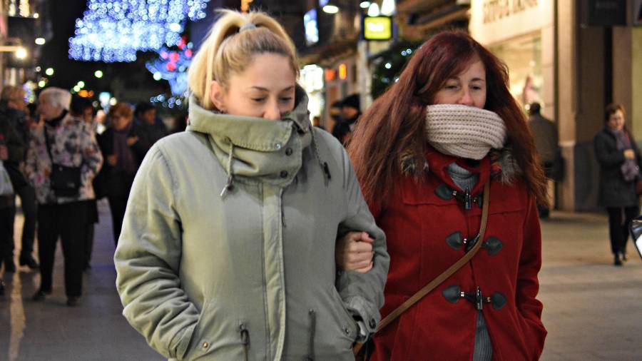 Dos mujeres se tapan del frío ayer por la tarde mientras pasean por la calle Llovera de Reus. FOTO: alfredo gonzález