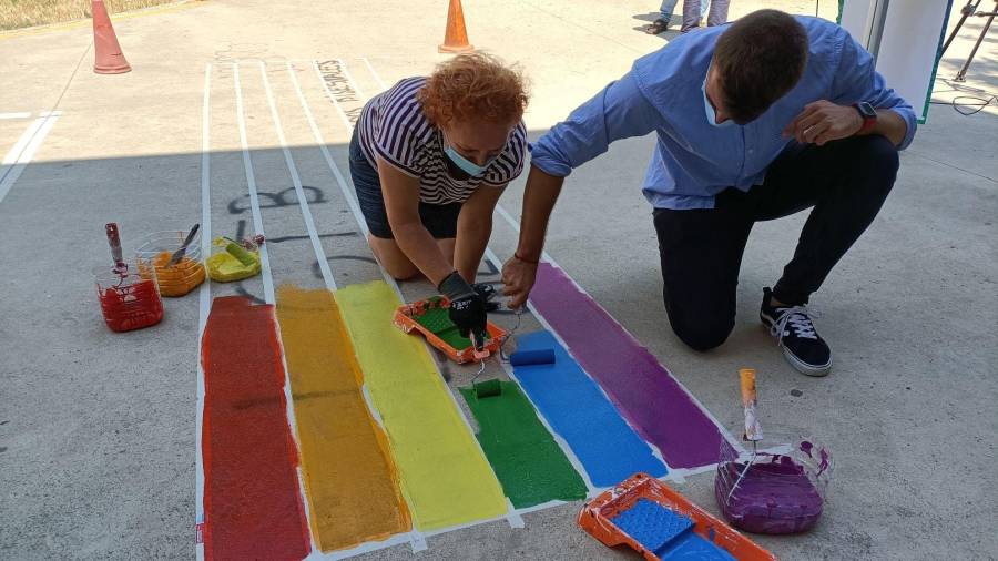 Concejales tapan la pintada homófoba con la bandera LGTBI.