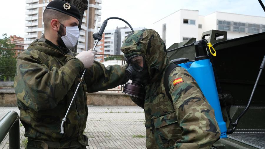 Un soldado ayuda a otro a prepararse para desinfectar. FOTO: Fabián Acidres