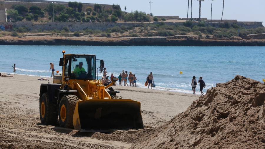 Esta semana en El Miracle convivían las máquinas que reponían la arena con los bañistas. FOTO: Pere Ferré