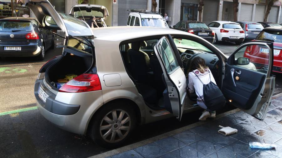 Una mujer limpia el interior de su coche afectado por el aguacero de las últimas horas. FOTO: ACN