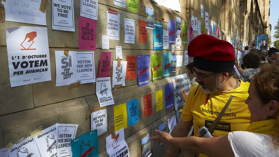 Varios estudiantes pegan carteles en la pared de la Universitat de Barcelona durante un acto de la ANC. Foto: efe