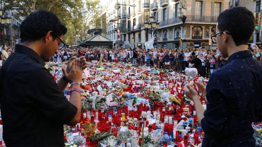 Dos joves aplaudeixen després d'haver fet l'ofrena a les víctimes dels atemptats de Barcelona i Cambrils.