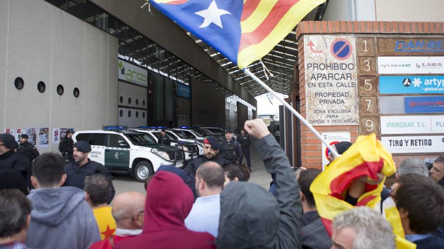 Simpatizantes independentistas protestan ante los agentes de la Guardia Civil, que han entrado en la imprenta Artyplan de Sant Feliu de Llobregat