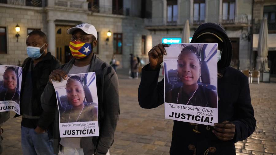 Dos personas muestran el cartel reclamando justicia en el caso de Peace Omonigho. FOTO: FABIÁN ACIDRES