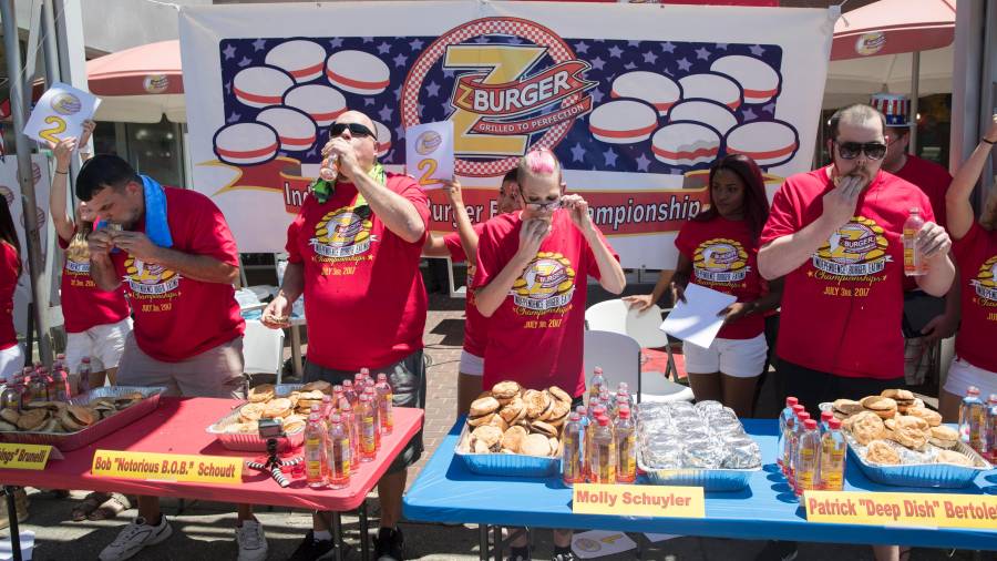 David Brunelli (i), Bob Shoudt (2i), Molly Schuyler (c) y Patrick Bertoletti (d) participan en el concurso de comer hamburguesas. Foto: EFE