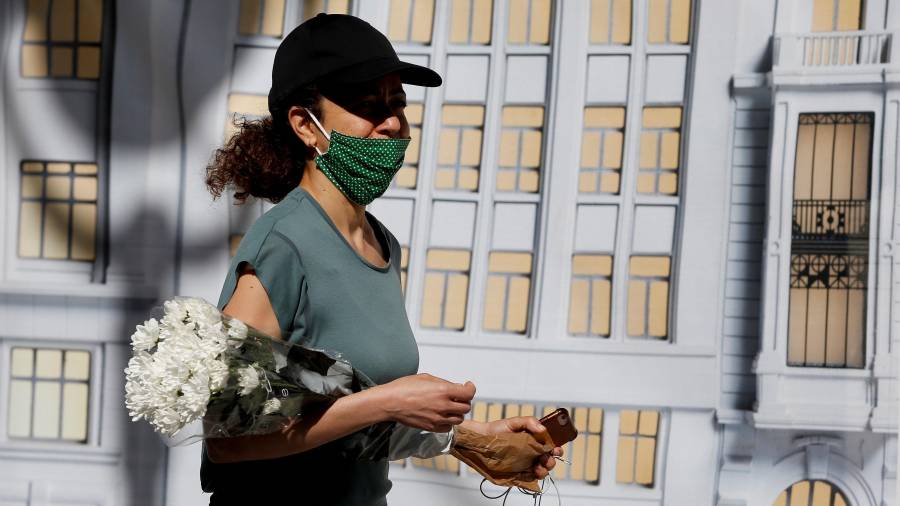 Una mujer lleva flores a un ser querido fallecido por coronavirus en el segundo día de luto. FOTO: EFE