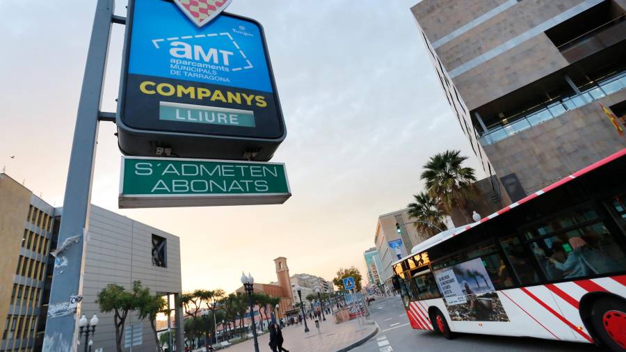 Un autobús municipal, ayer por la tarde, circulando frente al cartel de acceso al parking de Lluís Companys. FOTO: PERE FERRÉ