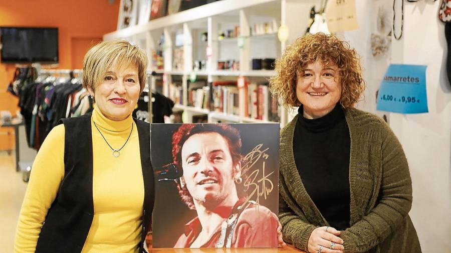 Cori (izquierda) y Estrella (detrás del mostrador) posan en la tienda Qui’k con la foto de Bruce Springsteen firmada por el cantante. FOTO: Alba Mariné