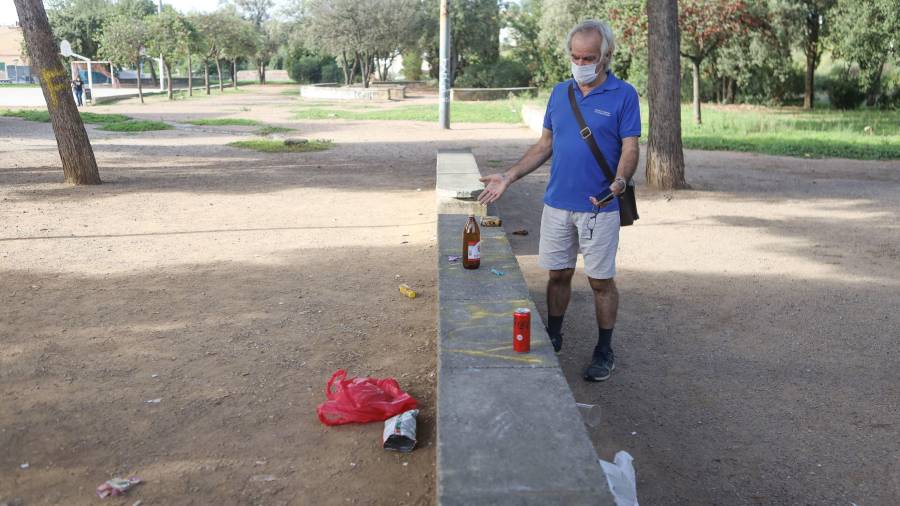 El presidente de la AV I de Maig, Eduardo Navas, muestra botellas y restos de comida alrededor del Centre Cívic Mas Abelló, ayer. FOTO: A. MARINÉ