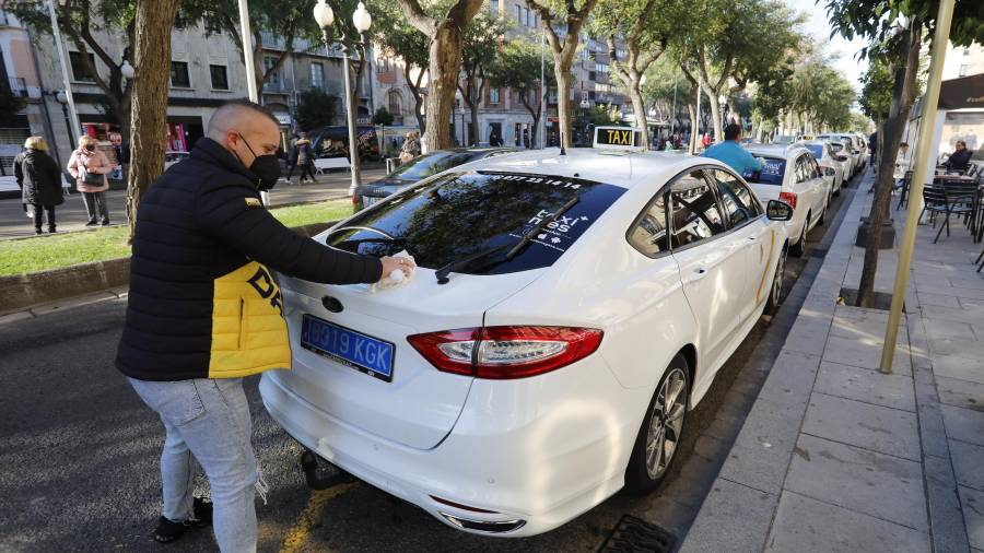Imagen de un taxista limpiando su coche en la Rambla Nova de Tarragona. foto: pere ferré