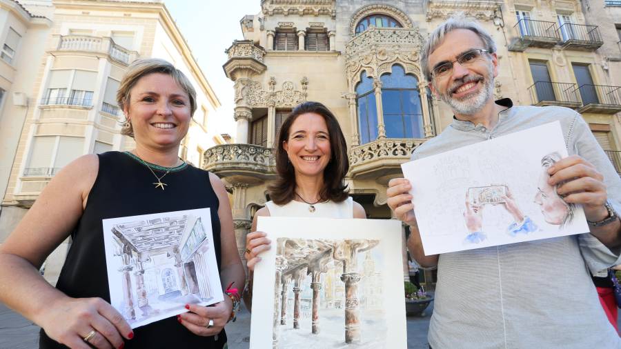 Elisabeth Tort, dissenyadora; Teresa Llorach, il·lustradora, i Eduard López, autor dels textos, mostrant algunes de les imatges que mostrarà el llibre, tot just davant de la Casa Navàs, al mig del Mercadal. FOTO: Alba Mariné