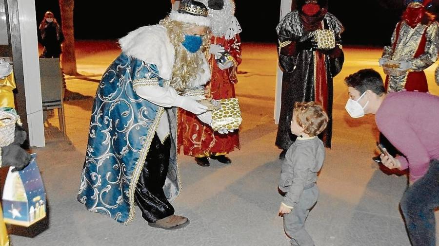 El rey Melchor entrega uno de los regalos a un niño en el paseo marítimo. FOTO: Aj. Torredembarra-Anna F.