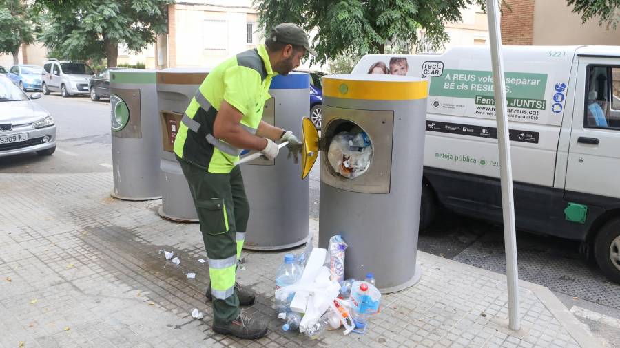 Un operario del servicio de recogida de la basura se encuentra ante un contenedor de plástico desbordado en Reus FOTO: ALBA MARINÉ