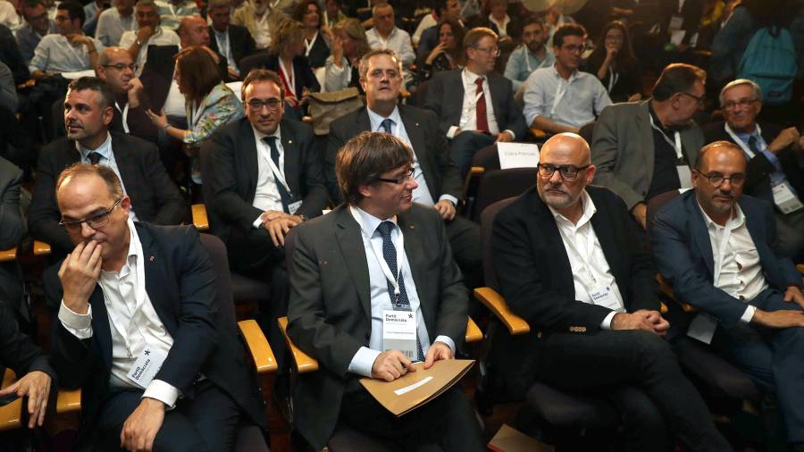 El presidente de la Generalitat, Carles Puigdemont (c), junto al conseller de la Presidencia Jordi Turull (i), y el presidente del grupo parlamentario de JxS, Lluís Corominas (d), al inicio de la reunión extraordinaria del consell nacional del PDeCAT. FOTO: EFE