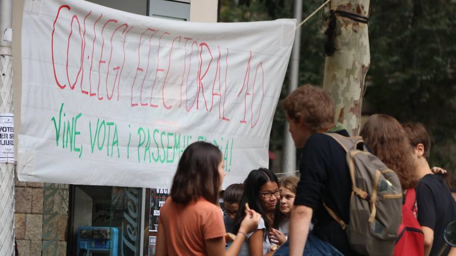 Imatge de la porta d'un institut amb alguns alumnes i la pancarta penjada que defensa el centre com a centre de votació pel referèndum. FOTO: ACN