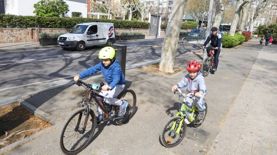 Jordi Viña con sus dos hijos en bicicleta por el Passeig Prim de Reus. FOTO: Alba Mariné