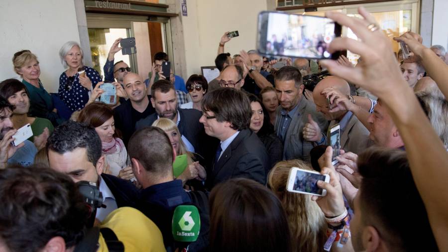 El presidente cesado de la Generalitat, Carles Puigdemont (c), acompañado por su esposa, Marcela Topor, tras almorzar en un céntrico restaurante de Girona en sus últimas horas en Catalunya