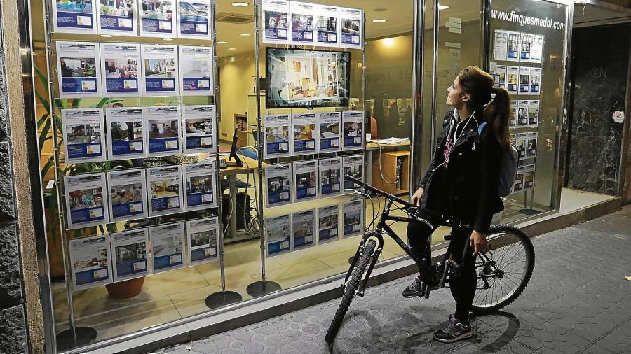 Una chica observa anuncios de viviendas en el escaparate de una inmobiliaria del centro de Tarragona. Foto: Lluís Milián