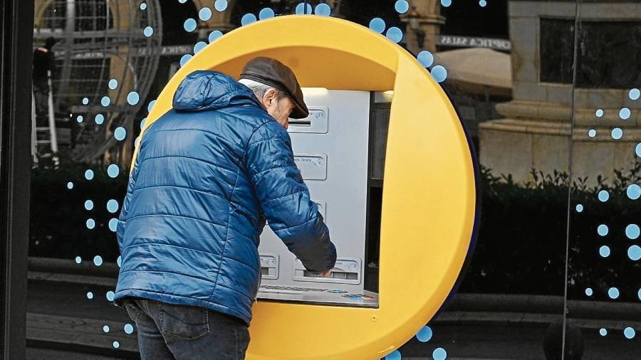 Una persona mayor utilizando un cajero automático de una entidad bancaria de la plaza Prim de Reus. FOTO: ALFREDO GONZÁLEZ