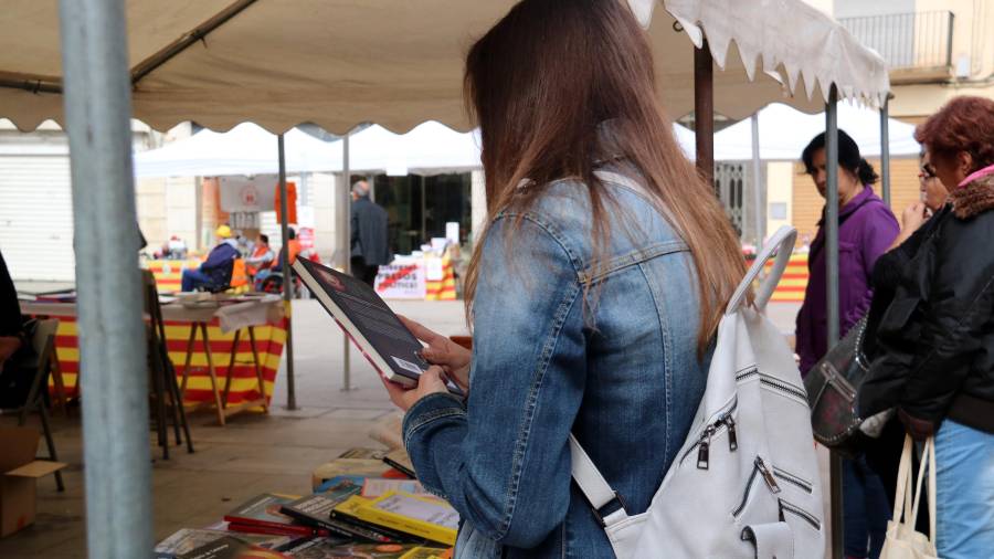 Una noia repassant la contraportada d'un llibre en una de les parades de Sant Jordi, a la Plaça de Dalt de Móra d'Ebre. FOTO: ACN