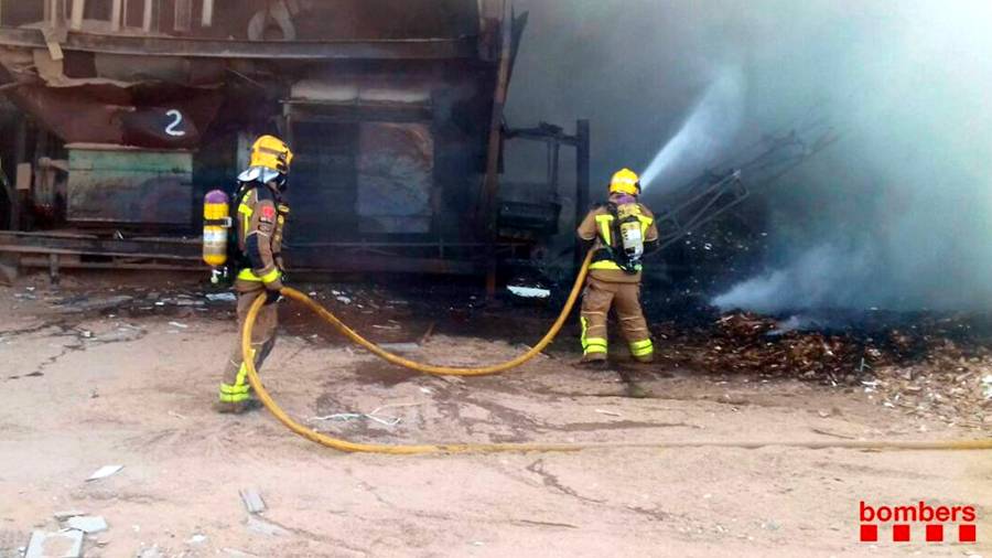 Dos bomberos apagando las llamas en esta empresa de Tortosa. FOTO: Bombers